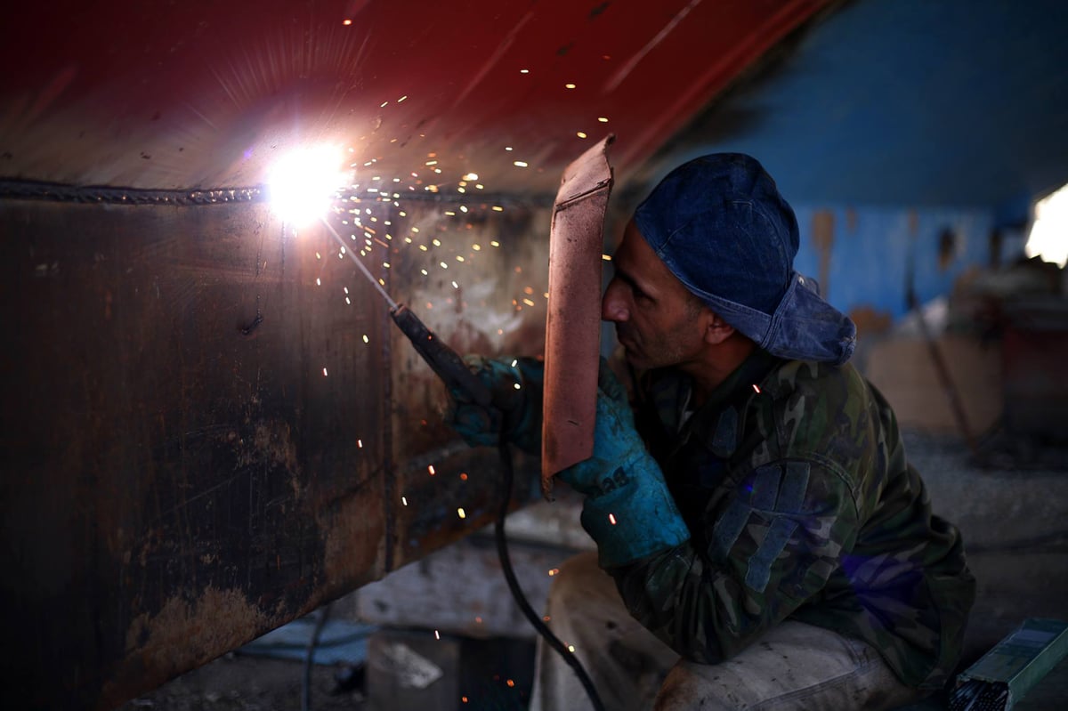 man-holding-welding-rod-and-welding-mask-while-working-236720